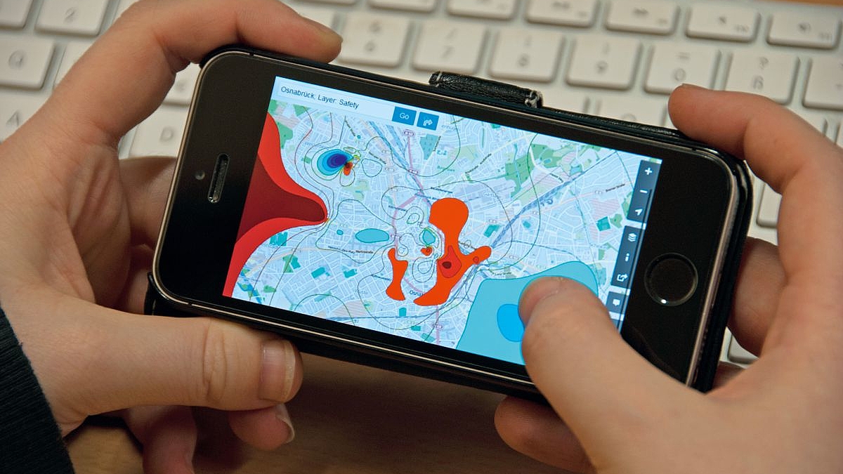 Auf dem Smartphone-Display ist eine Stadtkarte geöffnet. Bestimmte Orte sind farblich gekennzeichnet.