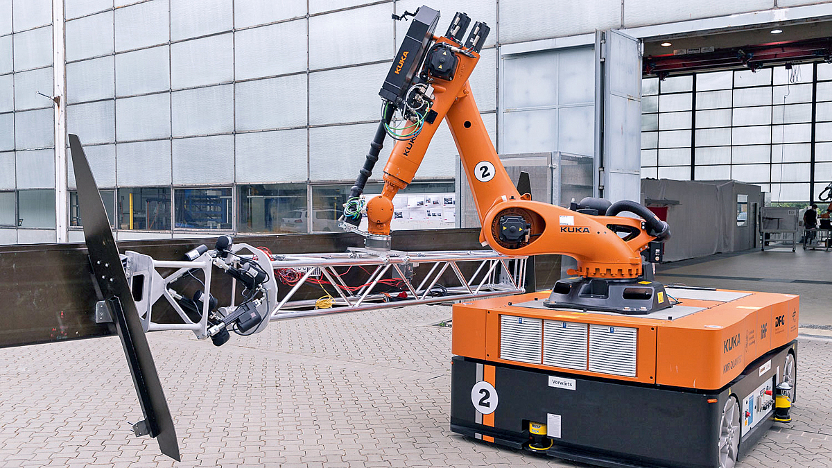 Roboterarm samt Gerüst hält die Landeklappe über dem Boden.