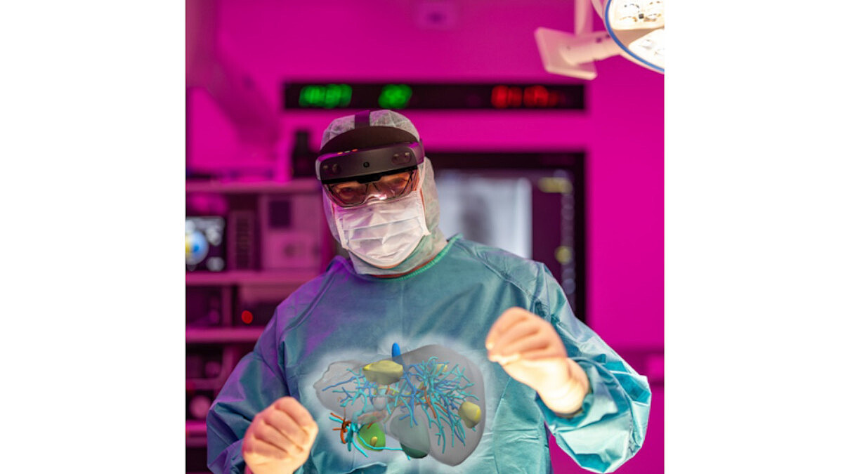 Eine Person in OP-Kleidung trägt eine VR-Brille. Vor ihr ist ein virtuelles Bild mit Gefäßen und Organen eingeblendet.