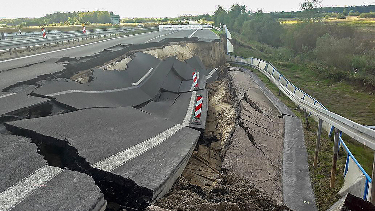 Ein Teil der Autobahn mit zwei Fahrspuren und Standstreifen ist einen Hang hinabgerutscht.