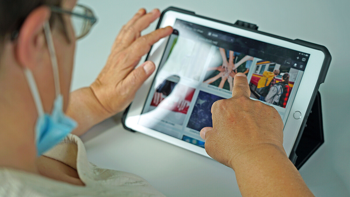 Ein Mensch navigiert durch das Programm auf dem Tablet.