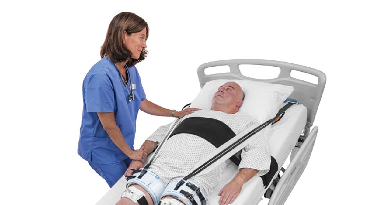 Eine Krankenschwester wendet sich einem Patienten zu, der in dem technisch ausgerüsteten Krankenhausbett liegt.