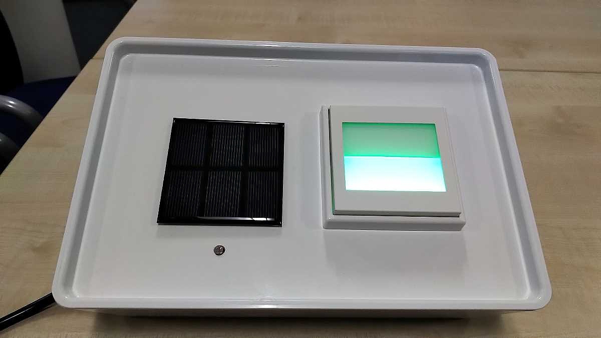 Ein Schalter mit transparenter Fläche in der Größe eines Lichtschalters leuchtet grün.