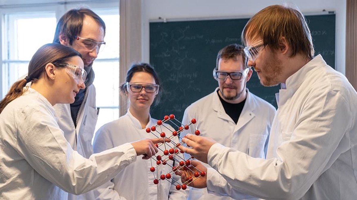 Chemikerinnen und Chemiker halten ein Molekül-Modell in der Hand und sprechen darüber.