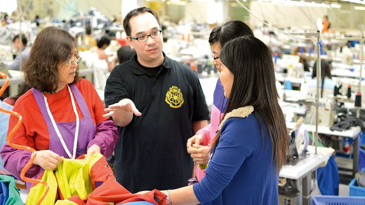 Prof. Dr. Nick Lin-Hi mit spricht mit Mitarbeitern eines Textilunternehmens in einer Produktionshalle.