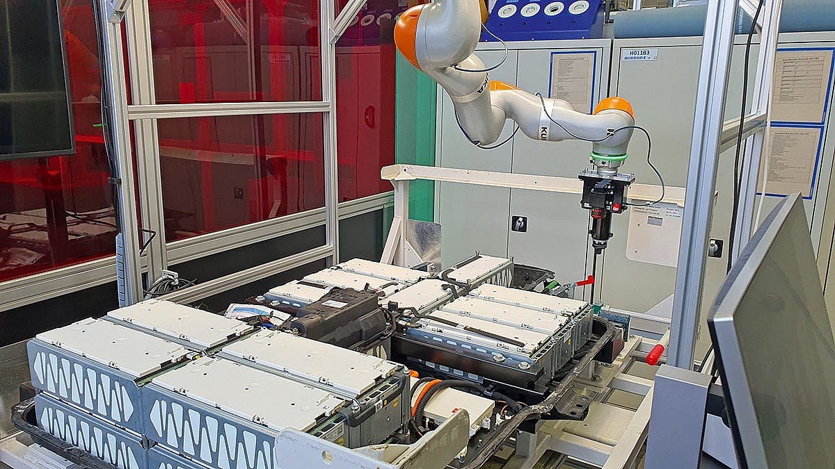 Ein Roboterarm schwebt über dem Deckel einer kastenförmigen Batterie.