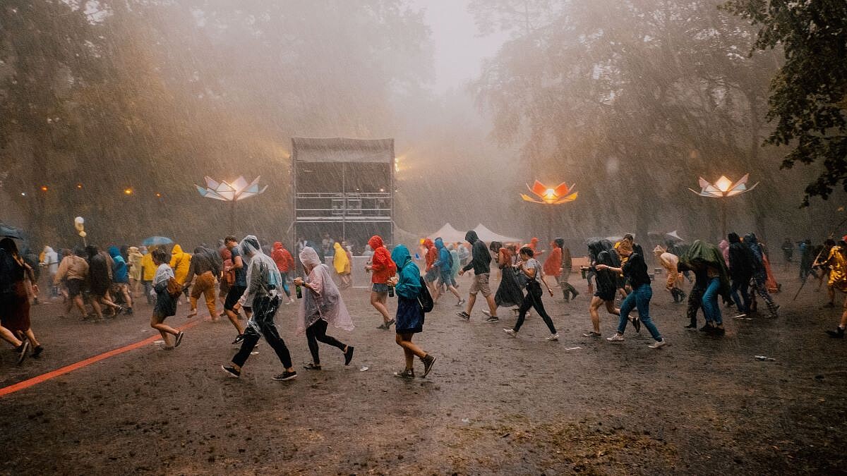 Im stürmischen Regen eilen Menschen in Regenkleidung von einem Festivalgelände.