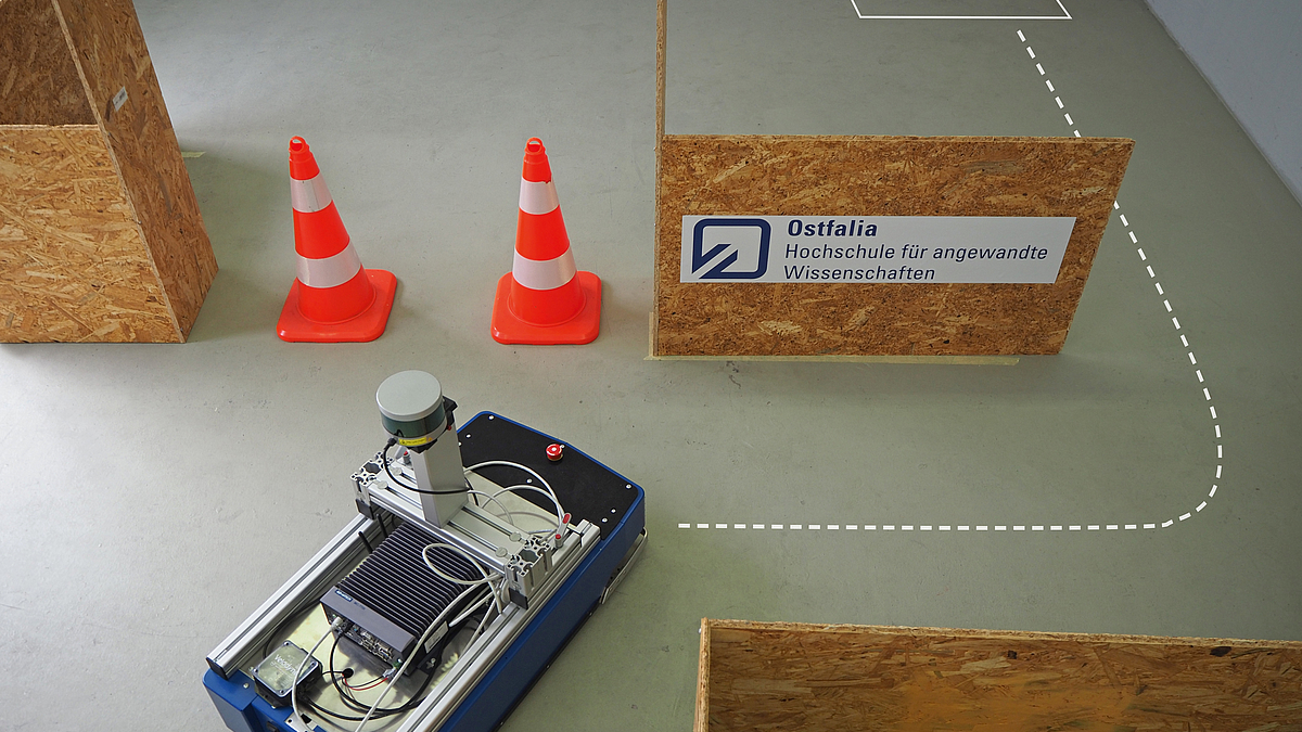 Ein Roboter fährt durch einen Hindernisparcours aus Platten und Leitkegeln