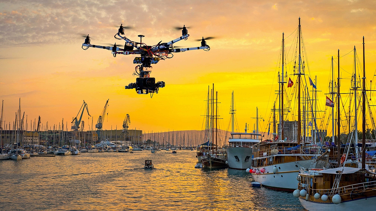 Eine Drohne mit einer integrierten Kamera fliegt am Hafen in der Luft