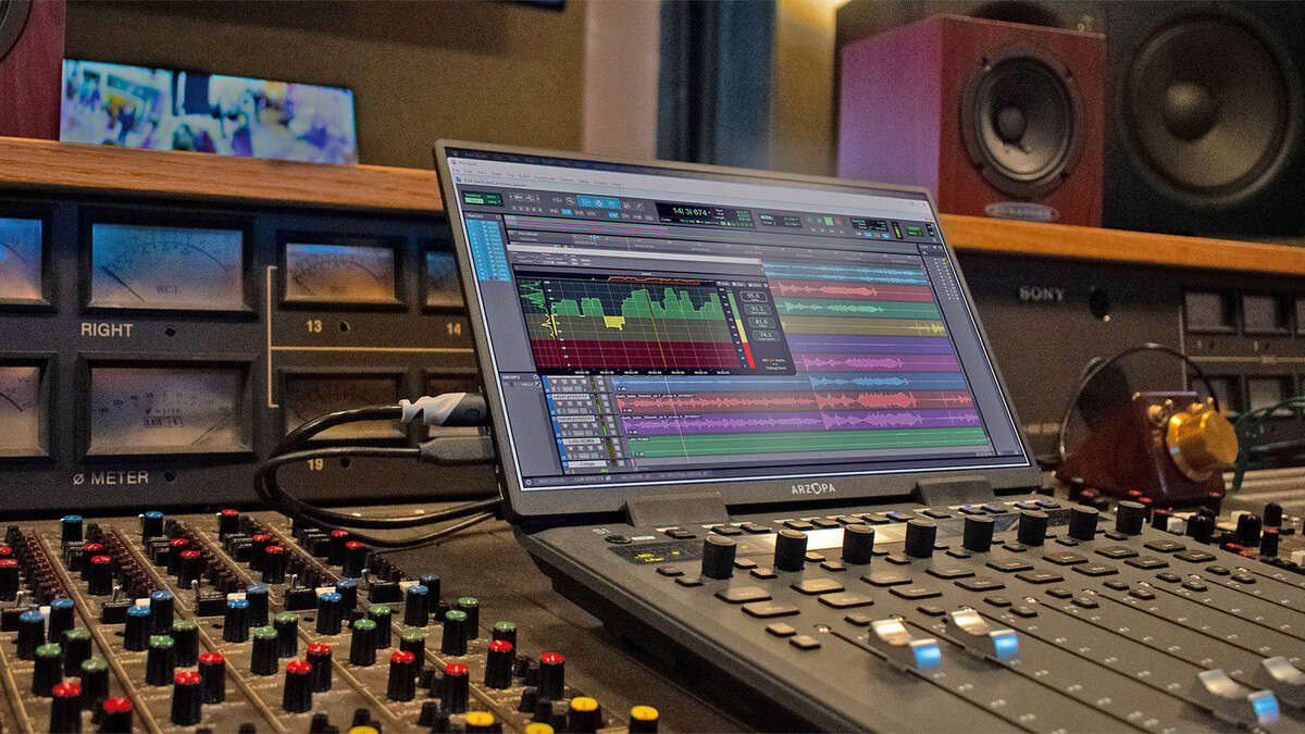 Ansicht eines Mischpults mit verschiedenen Dreh- und Schiebereglern. Auf einem Monitor sind Video- und Audiospuren sichtbar. Ein vorgelagertes Softwarefenster stellt die Sprachverständlichkeit der Audiospur in Form von grünen, gelben und roten Balken dar.