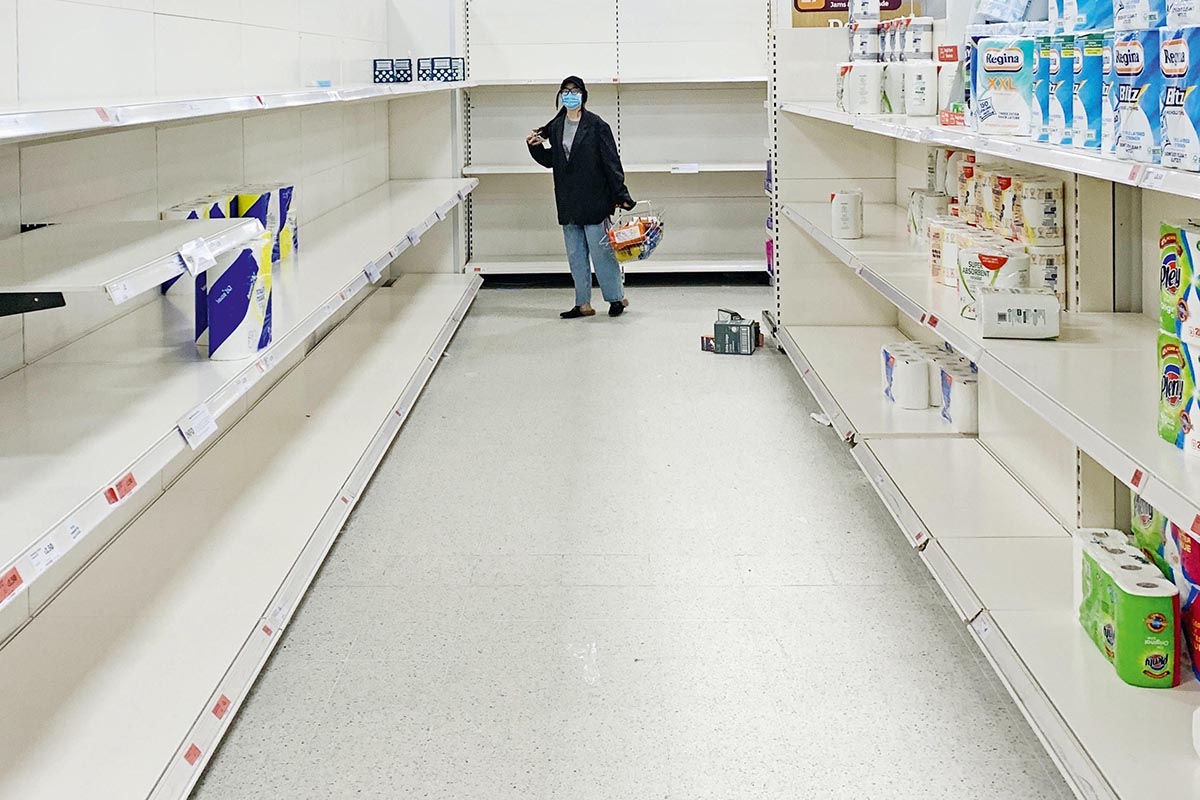 Eine Frau steht im Supermarkt vor leeren Regalen.