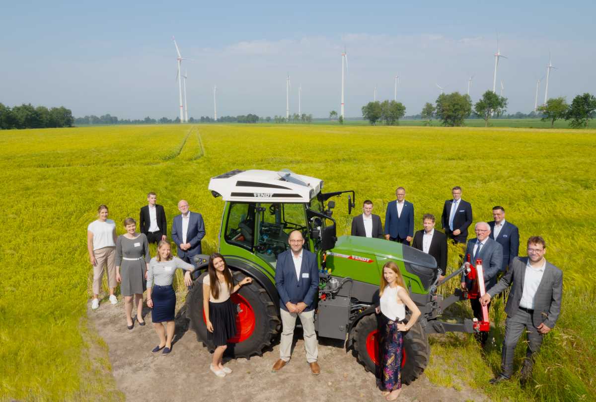 Gruppenfoto vor Traktor, Feld und Windpark