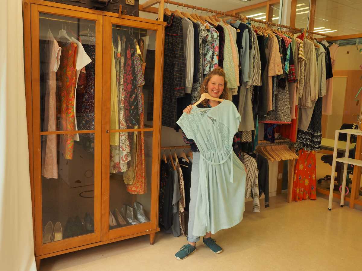 Die Studentin zeigt ein Kleid aus dem Angebot des Kleidungsverleihs.